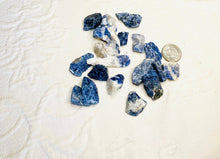 Load image into Gallery viewer, May include: A collection of blue and white sodalite rough stones. The stones are various sizes and shapes. A US quarter is included for size reference.
