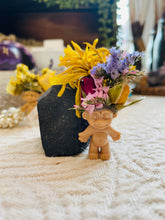 Load image into Gallery viewer, May include: A small, beige troll doll with a flower crown made of dried yellow, pink, and blue flowers. The troll doll is standing on a white surface.