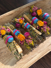 Load image into Gallery viewer, May include: Four bundles of dried herbs and palo santo wood sticks wrapped in yellow twine. Each bundle features a bright blue stone secured with pink thread, accented with dried yellow roses, pink rosebuds, and small yellow and purple wildflowers.