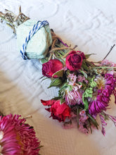 Load image into Gallery viewer, May include: A dried flower bouquet with pink and purple flowers, red roses, and a green stone wrapped in twine and blue and white ribbon.