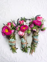 Load image into Gallery viewer, May include: Three bundles of dried herbs and flowers tied with twine and a green stone. The bundles are made with pink and purple flowers, rosemary, and lavender.