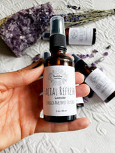 Load image into Gallery viewer, May include: A clear glass bottle with a black spray top filled with lavender facial refresh. The bottle has a white label with the text "FACIAL REFRESH Lavender CHARGED AMETHYST CRYSTALS 2 oz / 59 ml".
