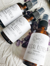 Load image into Gallery viewer, May include: Three amber glass bottles with black spray tops and white labels. The labels have the text "Facial Refresh" and "Lavender Charged Amethyst Crystals" on them. The bottles are sitting on a white surface with purple amethyst crystals.