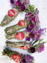Load image into Gallery viewer, May include: Bundles of dried herbs and flowers, including green sprigs, purple statice, and dried red strawberries, are tied with twine. Some bundles feature dried rose buds. The arrangement is set against a white, textured background.