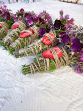 Load image into Gallery viewer, May include: Bundles of dried herbs and flowers, wrapped with twine. The bundles feature green herbs, purple flowers, and dried strawberry slices. The arrangement is set on a white, textured surface.