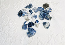 Load image into Gallery viewer, May include: A collection of blue and white raw Sodalite crystals. The crystals are various sizes and shapes, and some have a white, cloudy appearance.
