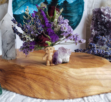 Load image into Gallery viewer, May include: A small, brown troll doll figurine with purple hair sits on a wooden surface. The doll is surrounded by a bouquet of purple and white flowers, including lavender and roses. The flowers are arranged in a vase made of clear glass.
