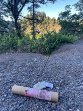 Load image into Gallery viewer, May include: A brown cardboard tube with a pink and white label that says "Therapeutic Clay Hand-Mixed Incense" and features a floral design. The tube is lying on a bed of small gray rocks. A gray incense holder and a stick of incense are also visible in the image.
