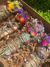 Load image into Gallery viewer, May include: Four bundles of dried herbs and flowers tied with twine, each containing a different crystal. The crystals are a clear quartz, a black tourmaline, a green aventurine, and an amethyst.
