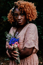 Load image into Gallery viewer, May include: A woman with curly brown hair wears a light pink, sheer, embroidered dress. She holds a bouquet of dried flowers with blue, pink, and white blossoms.

