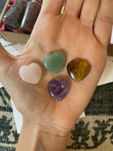 Load image into Gallery viewer, May include: Four heart-shaped crystals in various colors: green, pink, brown, and purple. The crystals are arranged on a hand.
