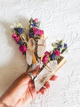 Load image into Gallery viewer, May include: Three bundles of dried flowers and herbs tied with twine and adorned with clear quartz crystals. The bundles are wrapped in wood and tied with twine.

