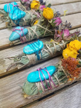 Load image into Gallery viewer, May include: Four bundles of dried herbs wrapped in twine, each featuring a bright turquoise stone secured with colorful wire. The bundles are decorated with dried yellow roses, pink rosebuds, and sprigs of purple lavender tucked into the stems.
