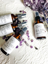 Load image into Gallery viewer, May include: Four amber glass bottles with black spray tops filled with lavender facial refresh. The bottles are labeled "Facial Refresh Lavender Charged Amethyst Crystals" and are arranged on a white surface with purple amethyst crystals.
