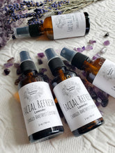 Load image into Gallery viewer, May include: Three amber glass bottles with black spray tops and white labels. The labels have a floral design and the text "Facial Refresh Lavender Charged Amethyst Crystals 2 oz/59 ml". The bottles are sitting on a white surface with purple amethyst crystals.
