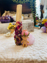 Load image into Gallery viewer, May include: A small pink troll figurine wearing a pink rose on its head. The troll is standing on a pink crystal next to a palo santo stick wrapped in dried rose petals.
