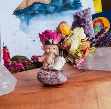 Load image into Gallery viewer, May include: A small plastic troll doll figurine with pink hair and a pink dress, standing on a small brown rock. The troll doll is holding a bouquet of dried flowers, including yellow, white, and pink roses.
