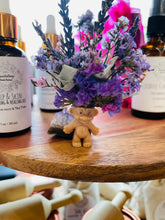 Load image into Gallery viewer, May include: A small, light brown troll doll with a purple flower crown made of dried lavender and other flowers. The doll is sitting on a wooden surface with two bottles of essential oil in the background.
