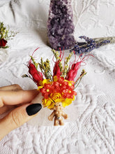 Load image into Gallery viewer, May include: A small plastic troll doll with yellow hair, wearing a crown of red and yellow flowers. The doll is sitting on a white surface.

