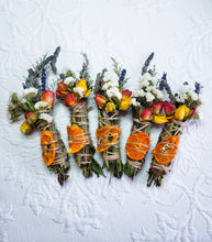 Load image into Gallery viewer, May include: Five bundles of dried flowers and orange slices tied together with twine. The bundles are arranged in a row on a white surface. The flowers are white, yellow, and orange. The orange slices are dried and have a brown color.
