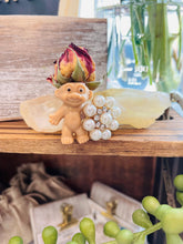 Load image into Gallery viewer, May include: A small plastic troll doll with a dried rose on its head. The troll is holding a pearl and rhinestone flower brooch.
