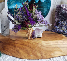 Load image into Gallery viewer, May include: A small, brown troll doll figurine with purple hair sits on a wooden surface. The doll is surrounded by a bouquet of purple and white flowers, including lavender and roses. The flowers are arranged in a vase made of clear glass.
