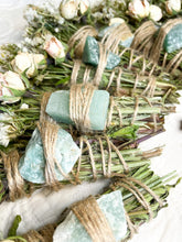 Load image into Gallery viewer, May include: A collection of smudge sticks wrapped in twine and tied with a green crystal. The sticks are made of dried herbs and flowers.
